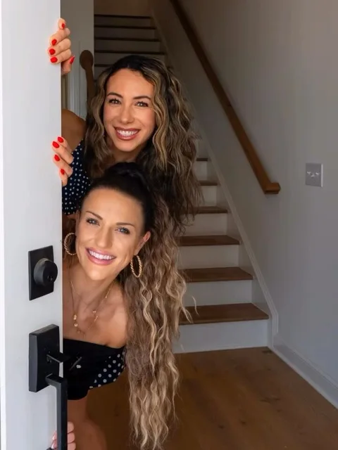Emily Mitchell and Emma Douglass peeking around a front door